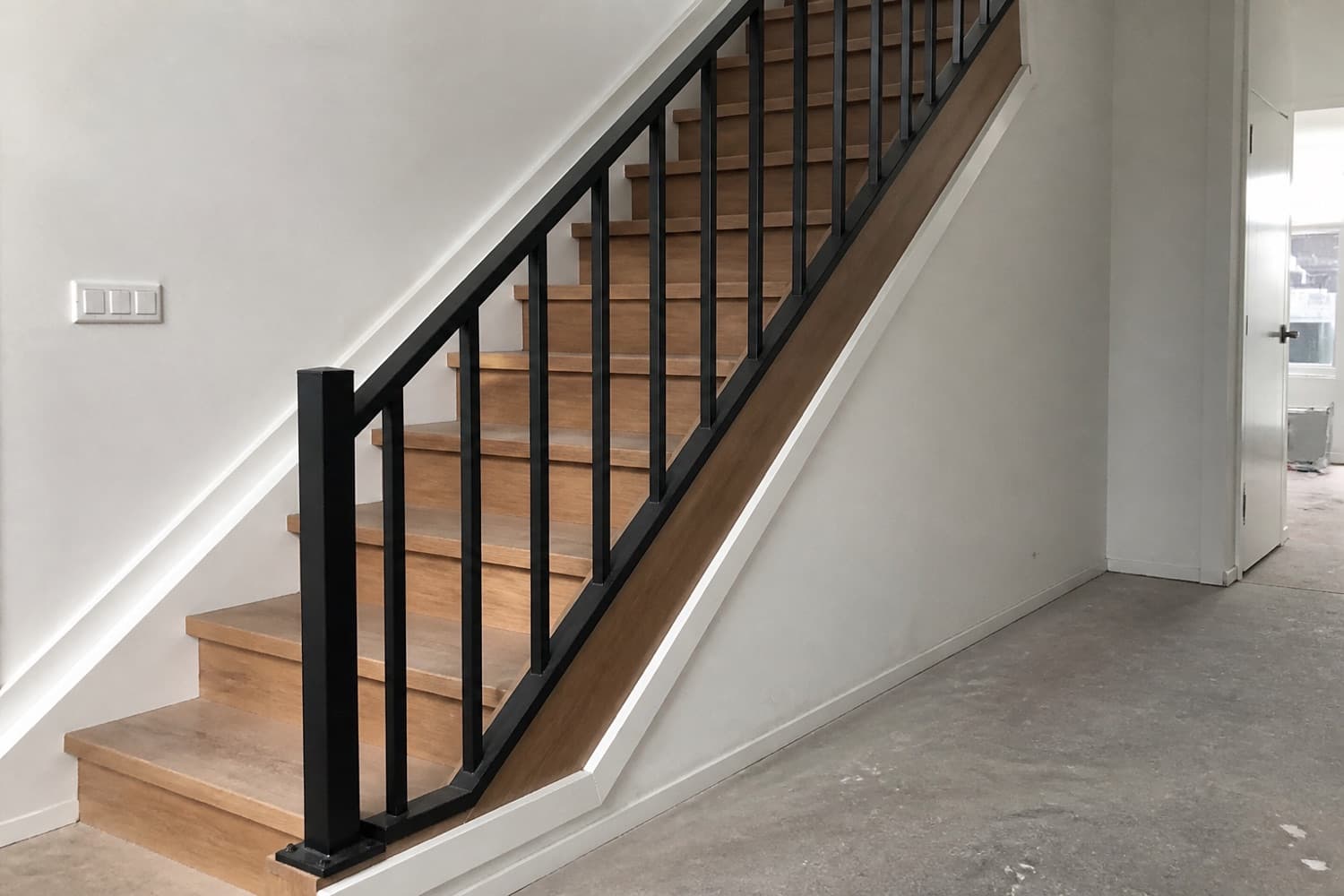 Zwart stalen balustrade met gelaste verbindingen langs een trap in een woning
