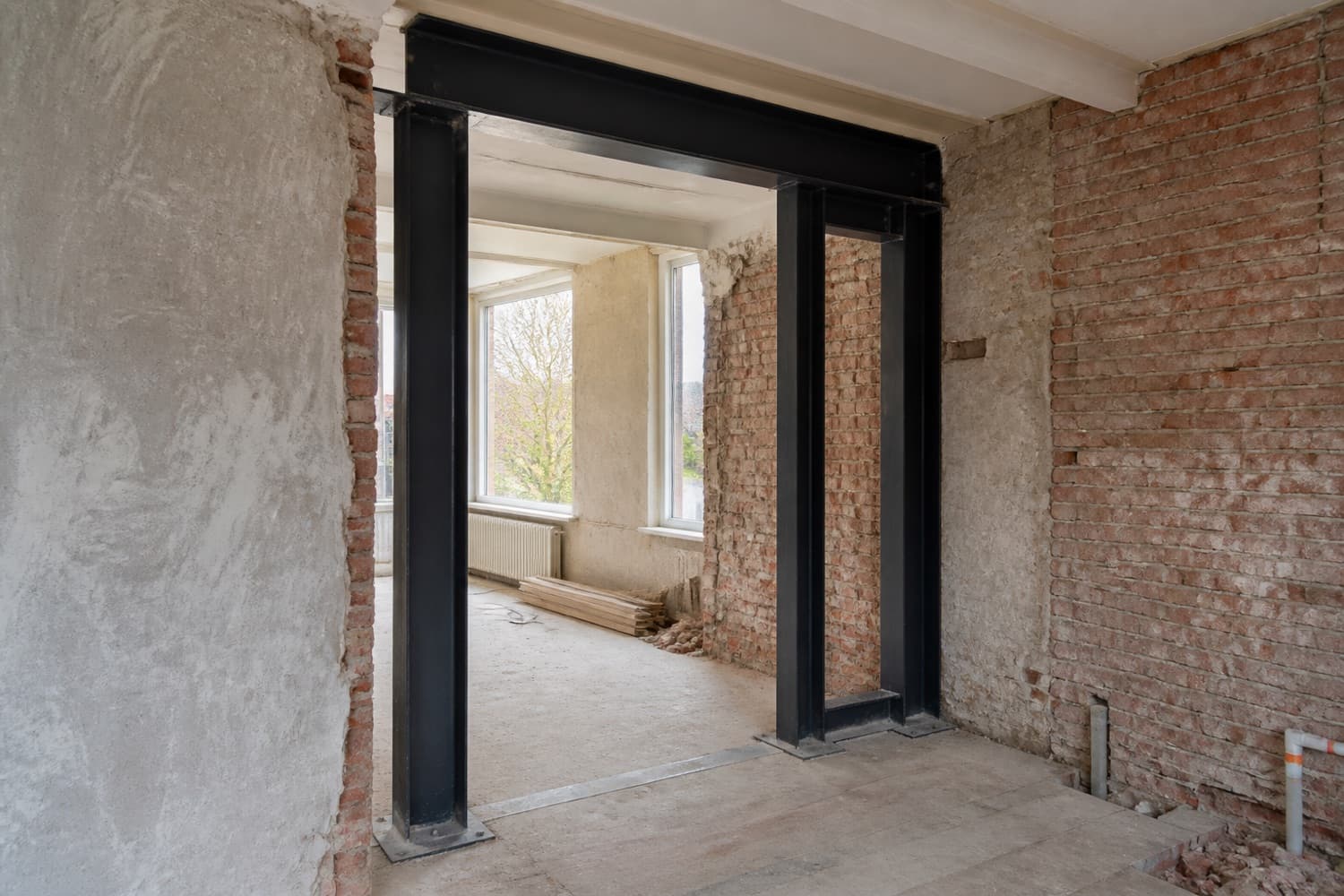 Zwart stalen portaal geplaatst in een woning die verbouwd wordt, tussen bakstenen muren
